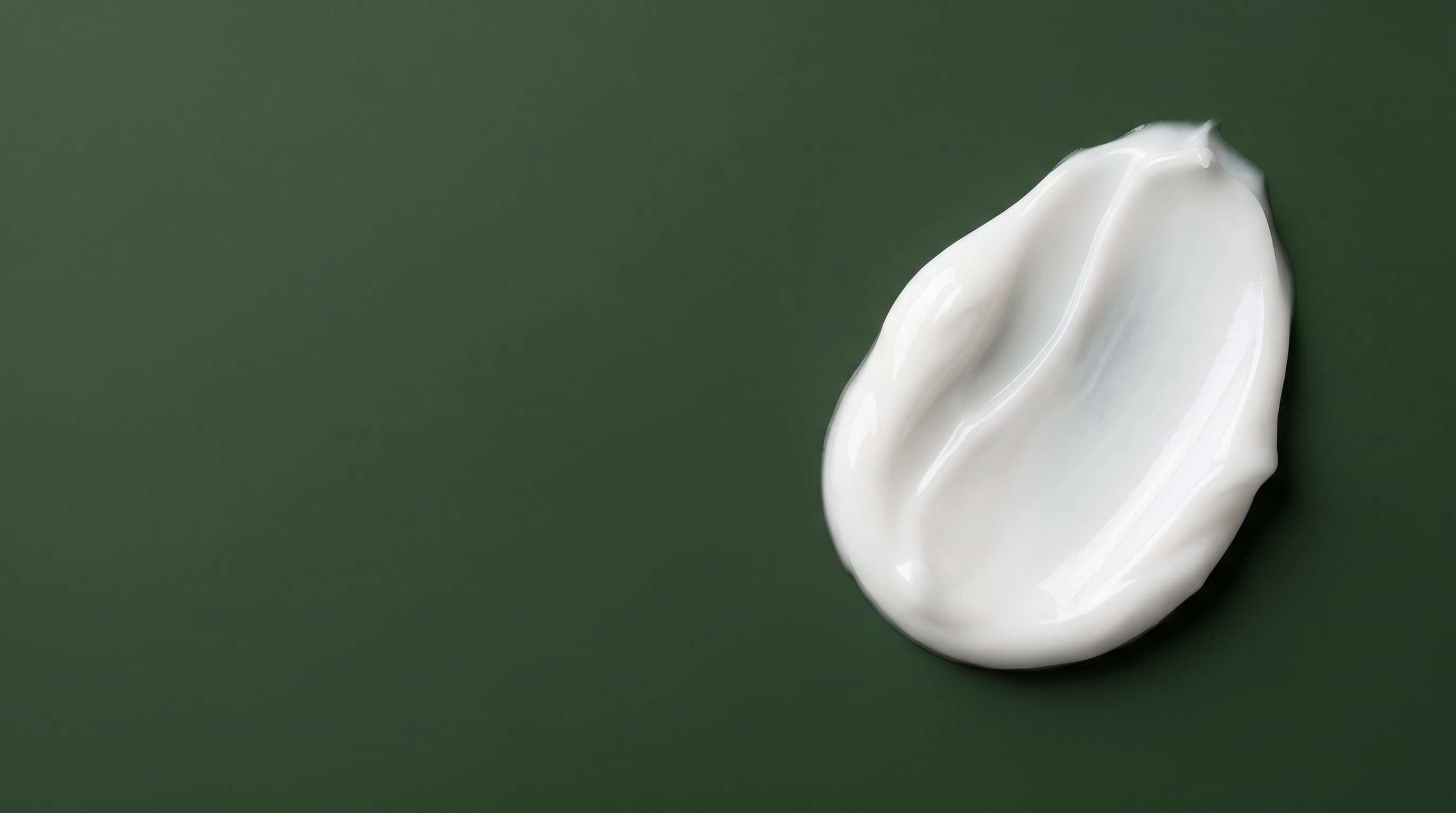 Textura de creme branco do Sérum Uniformizador Cultiva sobre superfície verde-mata