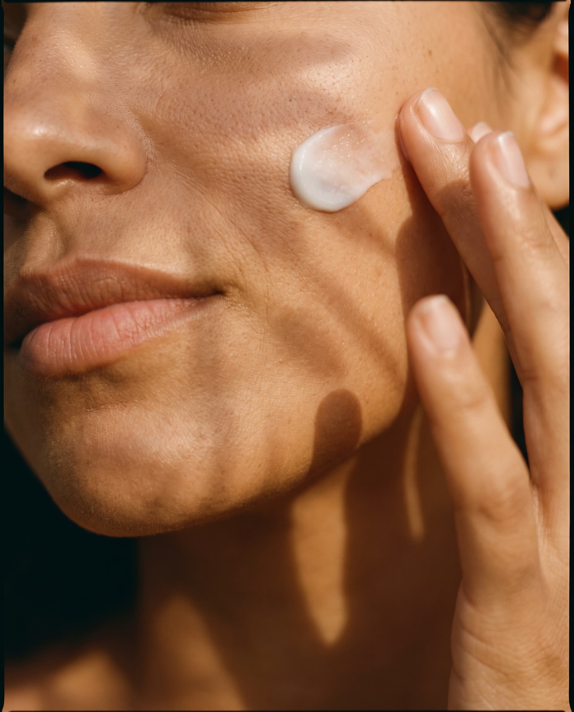 Pele com textura real recebendo creme branco sob a luz dourada da manhã